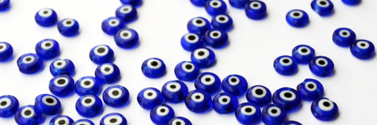 photo: blue evil eye beads scattered on a white background