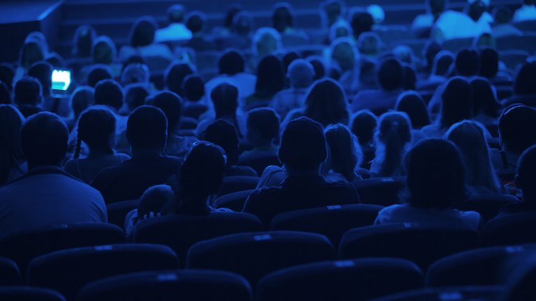 Audience seated in a darkened theatre