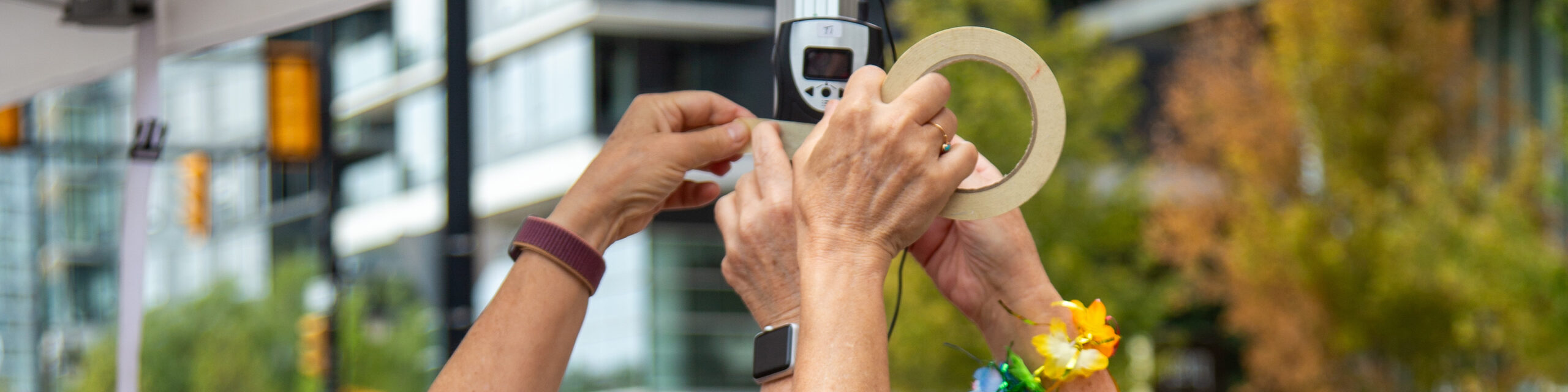 volunteers tape the describer's transmitter to a pole at Vancouver Pride 2023