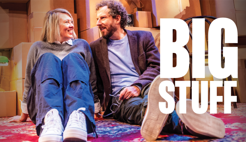 Actors Matt Baram and Naomi Snieckus sit onstage looking at each other, smiling. Large text reads: "BIG STUFF".
